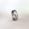 Platinum hammered band with an organic, sculptural shape, set with scattered coloured diamonds in varying sizes.