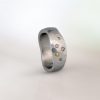 Platinum hammered band with an organic, sculptural shape, set with scattered coloured diamonds in varying sizes.