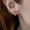 solid 18ct yellow gold hinged hoop earring with white brilliant cut diamond, shown on model's ear. Earring sits hugging the earlobe.
