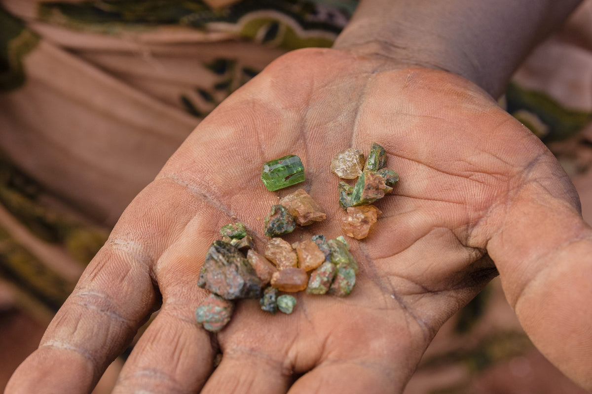 hand holding ethically sourced rough gemstones from Moyo Gems